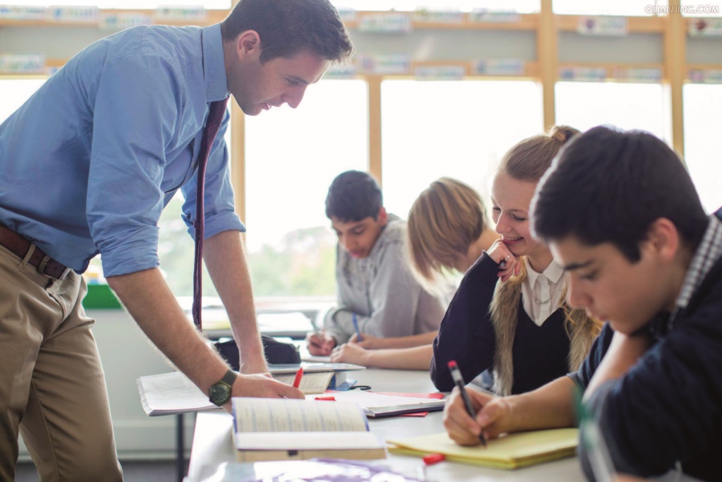 Male teacher helping secondary pupils in class