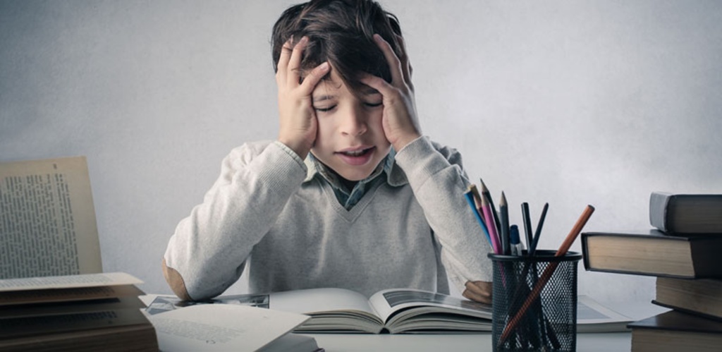 Child with hands on head while reading