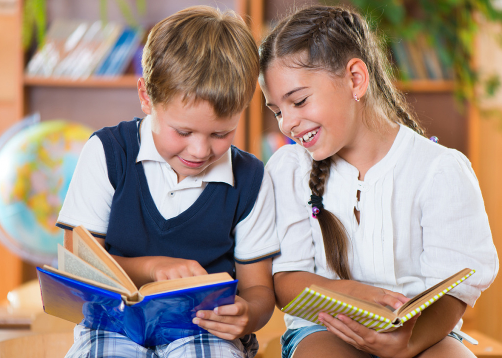 Two happy schoolchildren have fun in classroom at school.