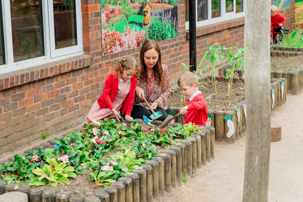 Primary school pupils and teacher growing plants in a garden