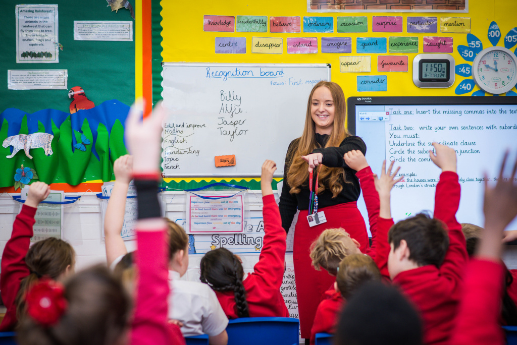 Teaching assistant leading a class of primary school pupils