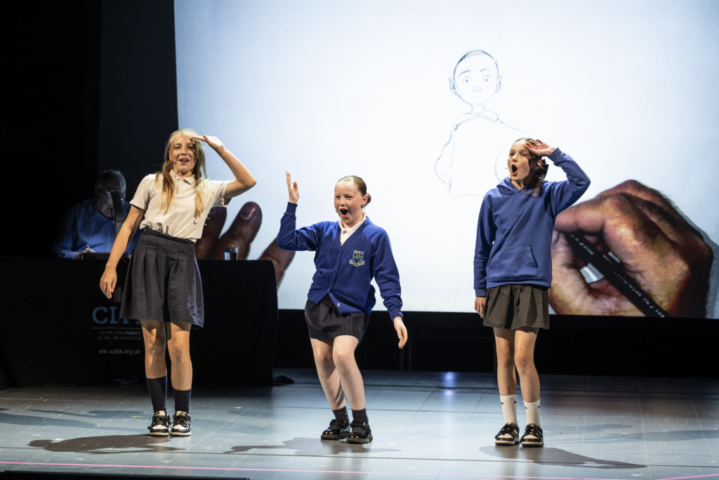 Three primary school girls performing poetry live on stage.