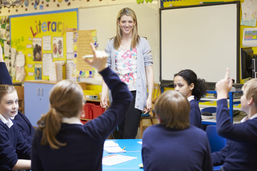 Primary school girl raising her hand in a languages classroom