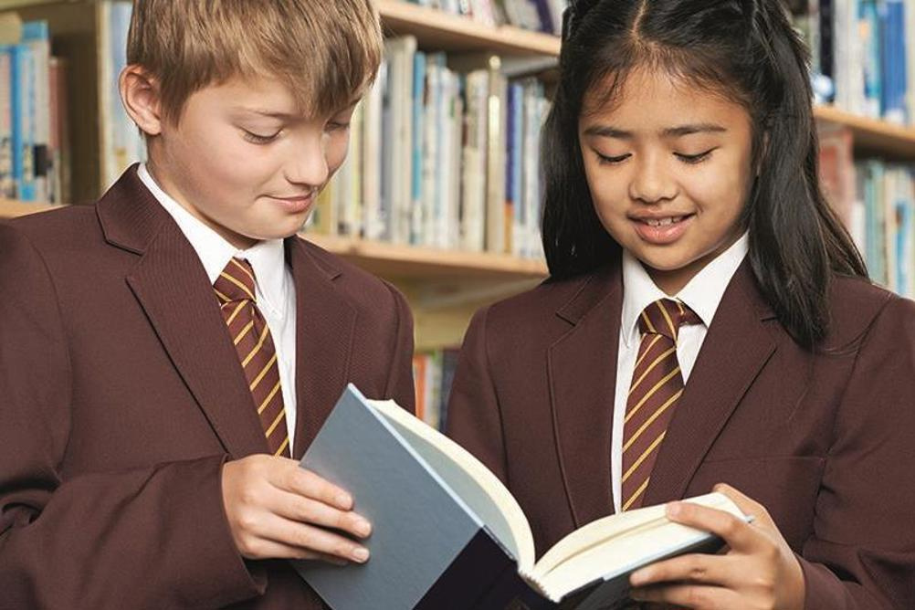 Secondary school boy and girl reading a book together.