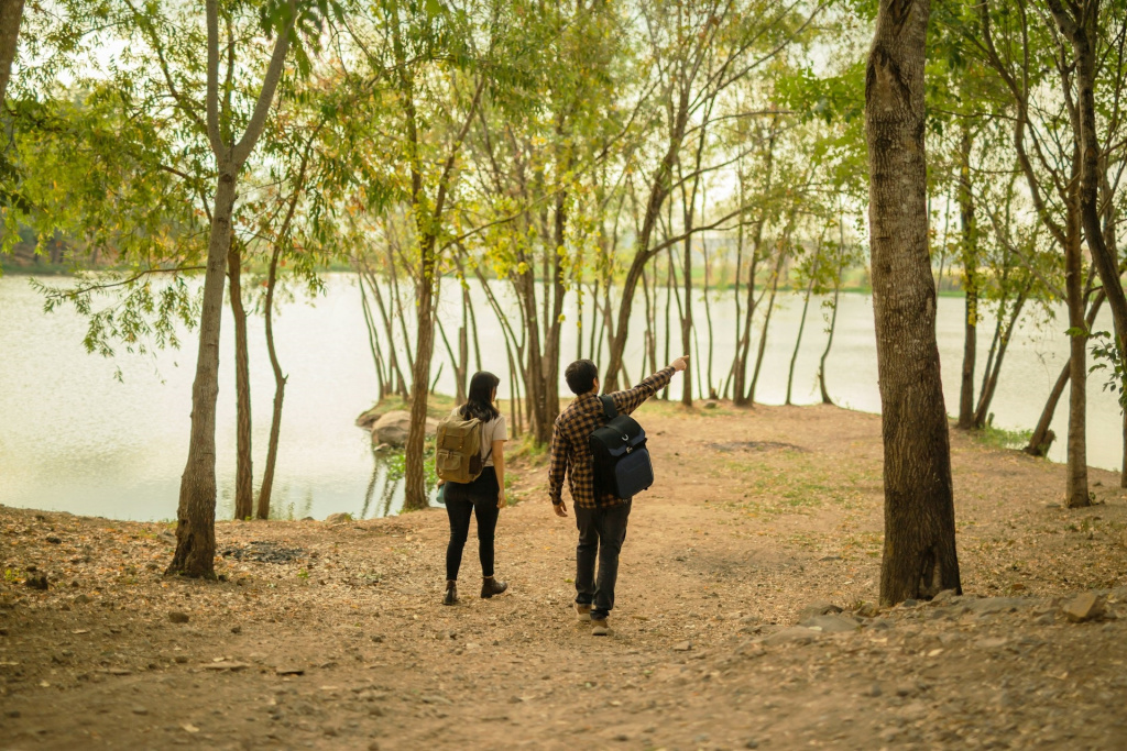 Secondary school girl and boy walking between trees near a lake.