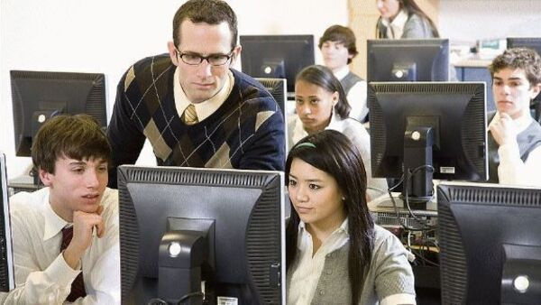 Secondary school students and teacher looking at computer screens