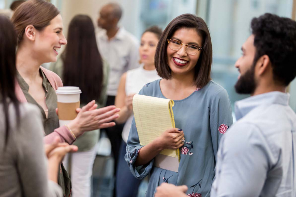 Smiling teachers talking in a group in a staff room.