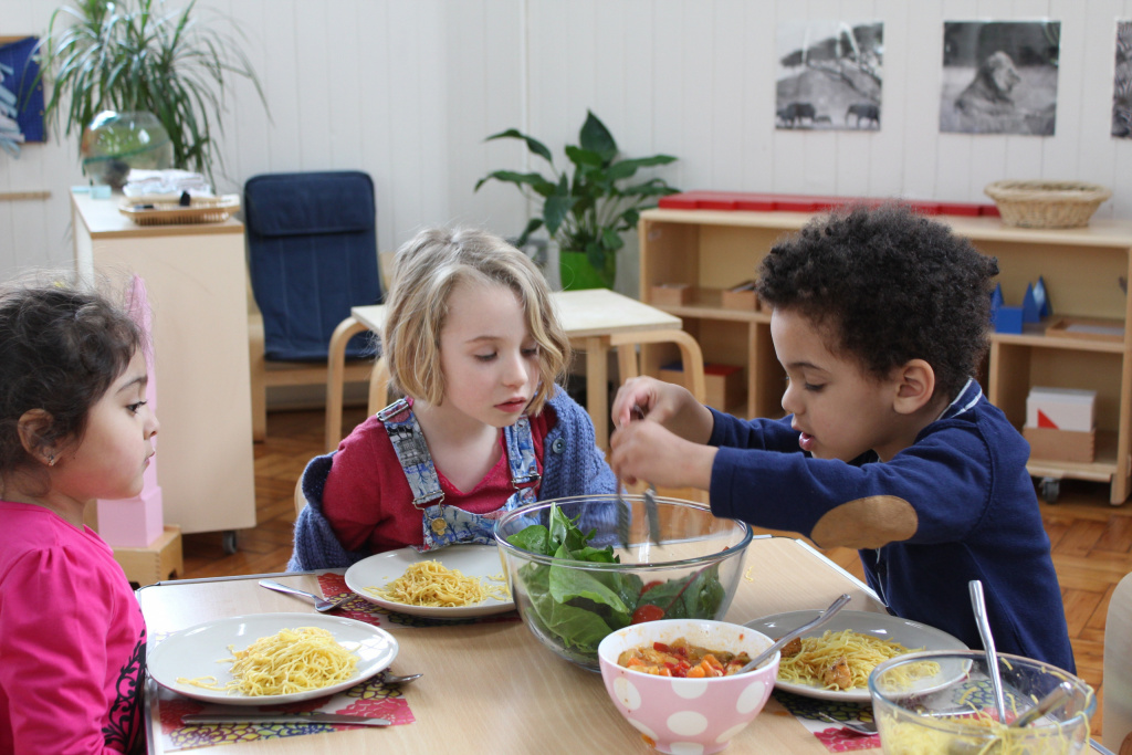 Three primary school children preparing food in a classroom