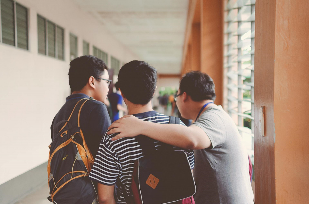 Three teenage boys standing together in a secondary school corridor.