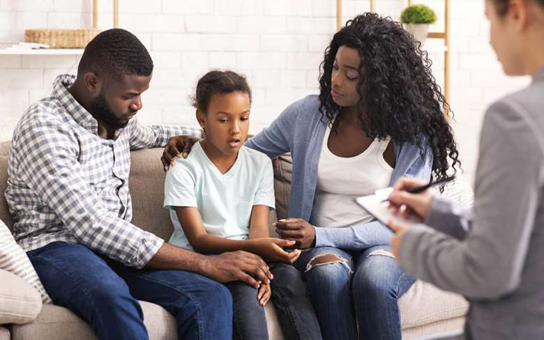 Professional conducting a home visit with a young black family.