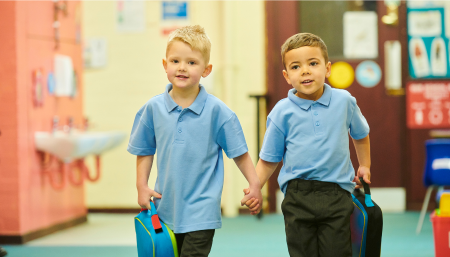 Two primary school boys holding hands in a corridor