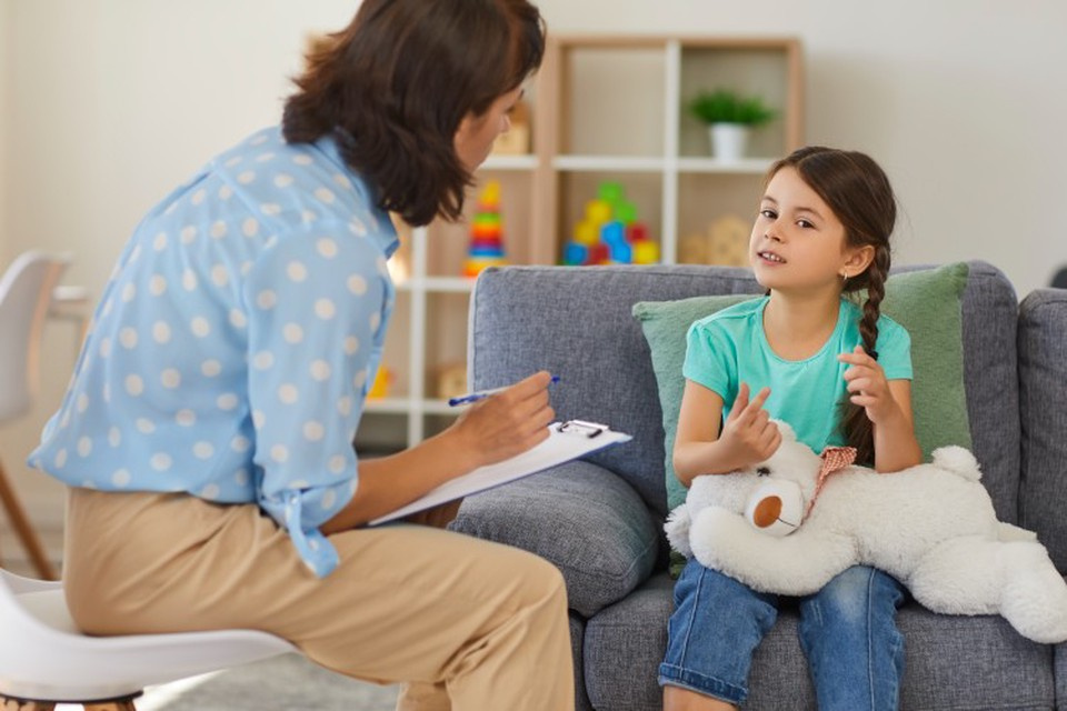 Young female professional speaking with primary school girl at home