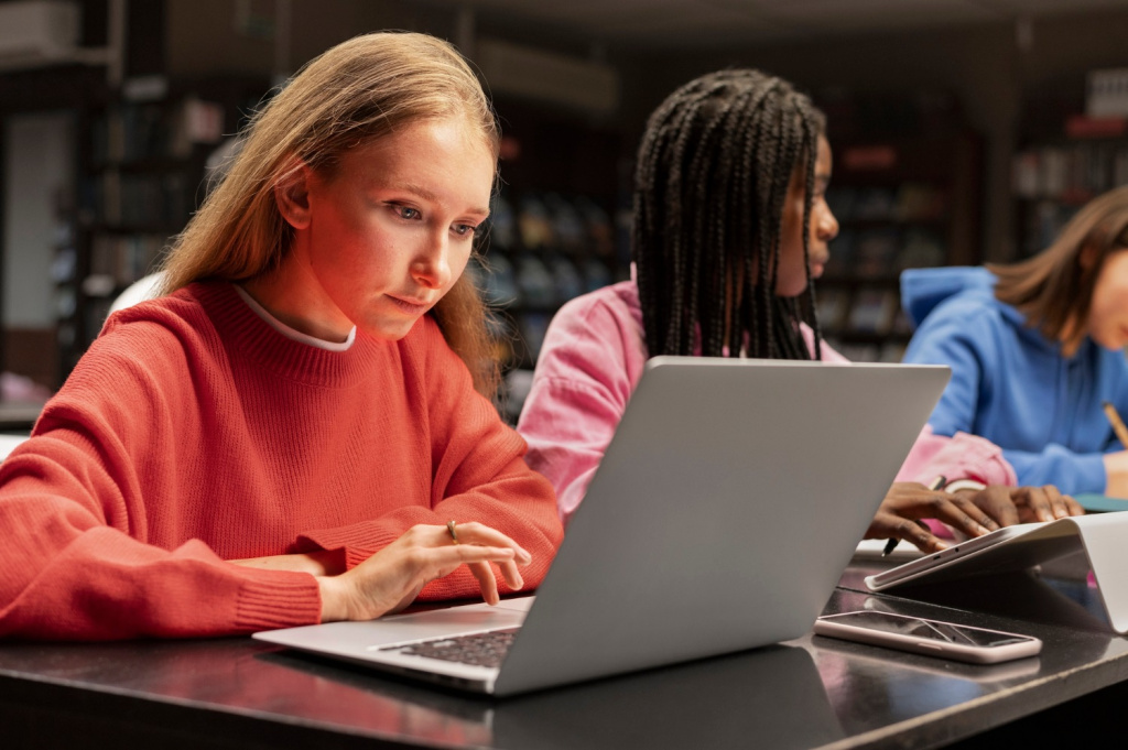 Female students using laptop computers to study in a library.