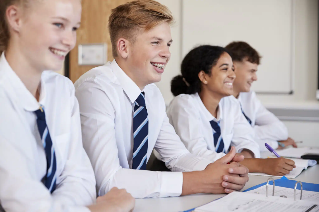 Group of secondary schoolers smiling in a classroom.