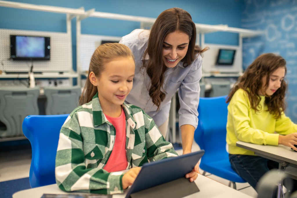 Secondary school teacher helping girl with an iPad.