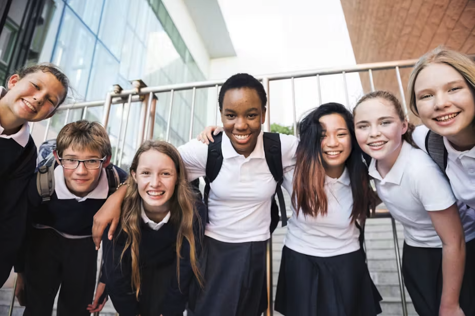 Smiling primary school pupils standing in a row outdoors.