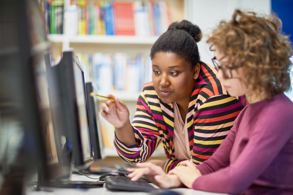 Tutor helping secondary school student use a computer.