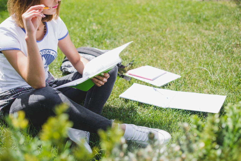 Secondary school girl reading outside in nature.