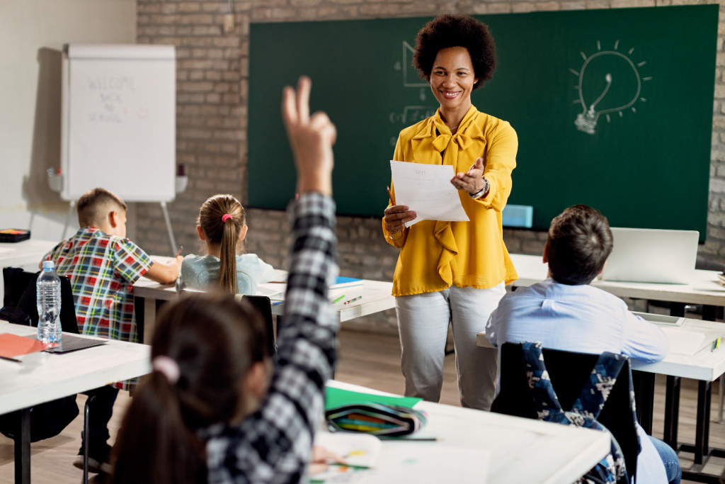 Black female teacher asking pupils questions in class.