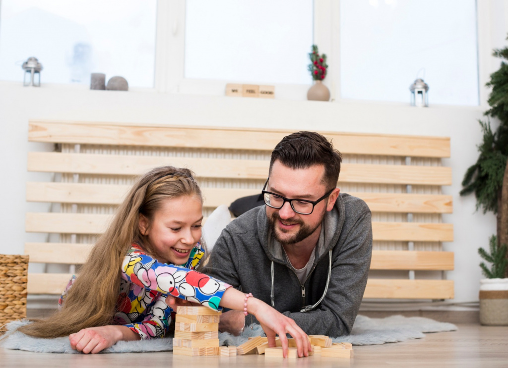 Father and daughter playing together with wooden blocks.