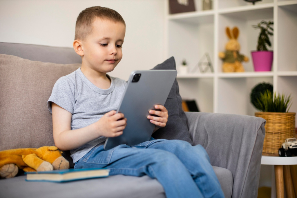 Young primary school boy using iPad or other tablet at home.